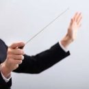 116478601-close-up-of-a-music-conductor-hands-holding-baton-sur-fond-gris